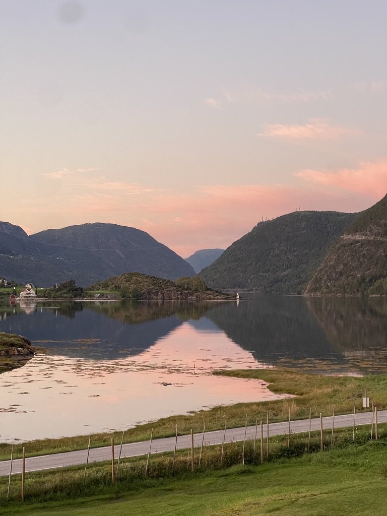 Stille kveld ved Sognefjorden, med rosa himmel og fjellene speilet i det blanke vannet
